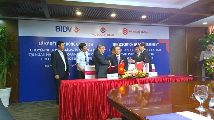 Đại diện BIDV (trái) và VID Public Bank bắt tay trong lễ ký kết chuyển nhượng vốn góp vào tháng 7-2014