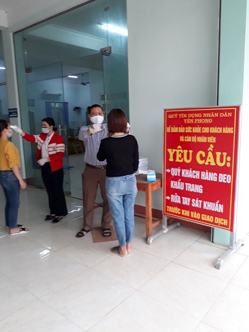 QTDND Yên Phong - Thanh Hóa đo thân nhiệt cho thành viên trước khi vào giao dịch tại Quỹ. 
